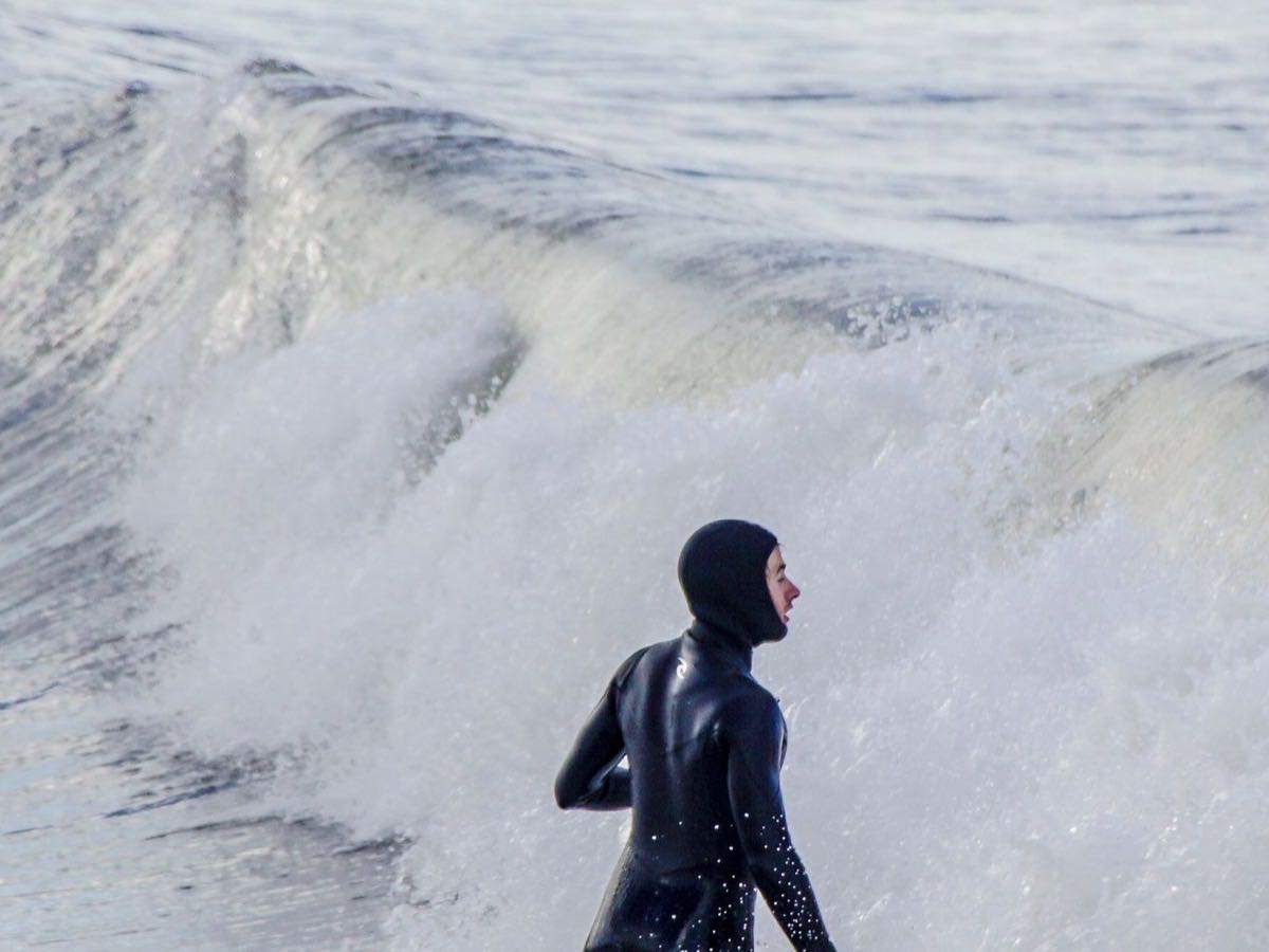 Surfer standing near breaking waves